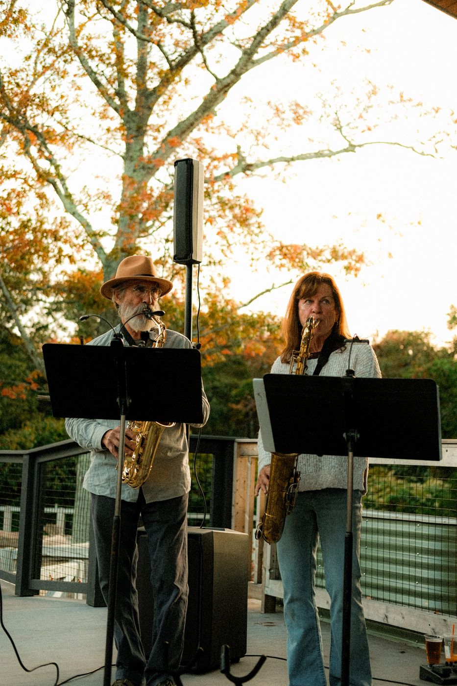 The two saxophone players on an outdoor deck at sunset