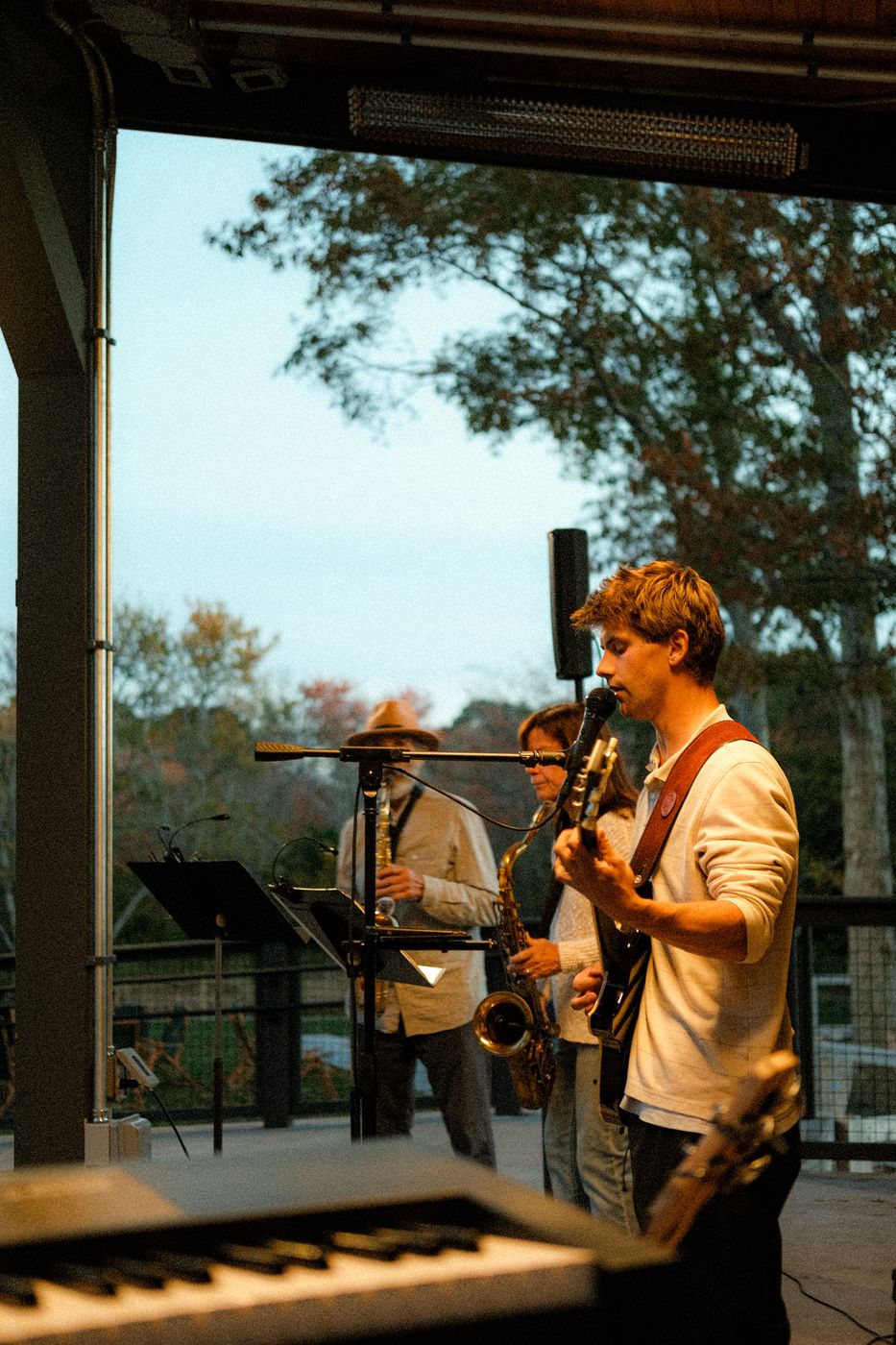 The band playing under a covered porch stage at dusk